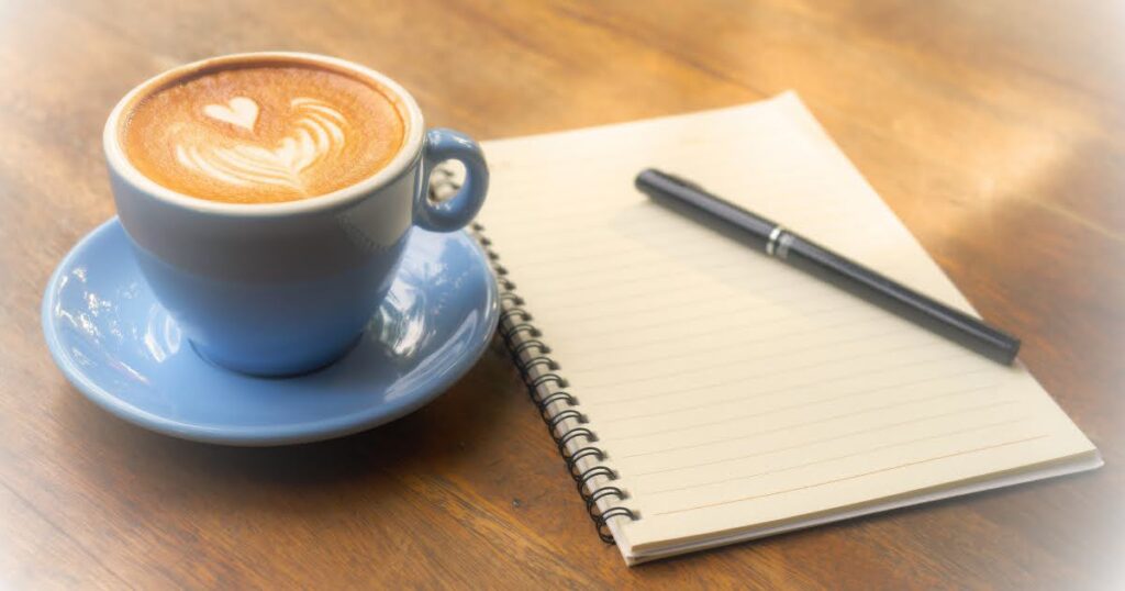 カフェラテ、ノート、ペンの画像