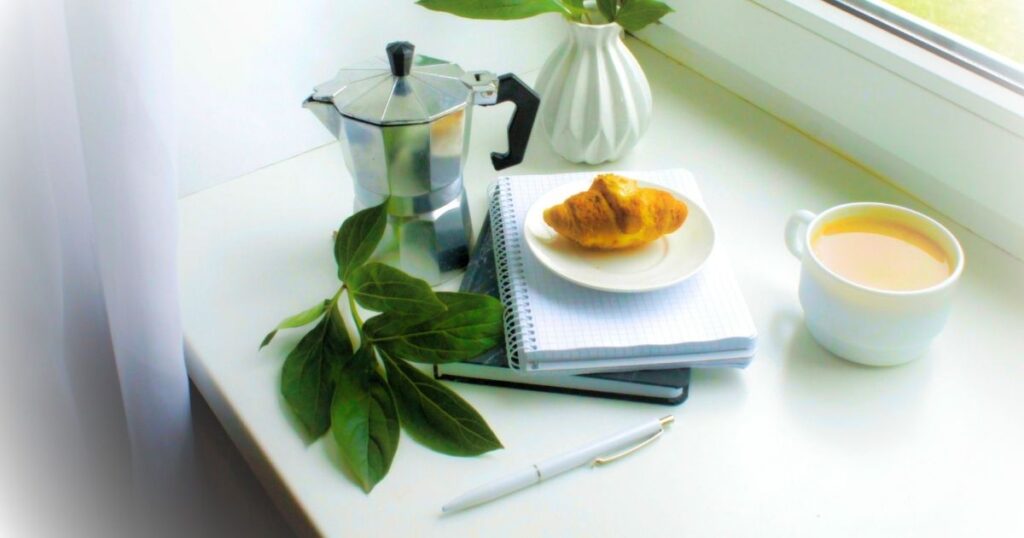 葉っぱとクロワッサン、コーヒーが置かれたデスク